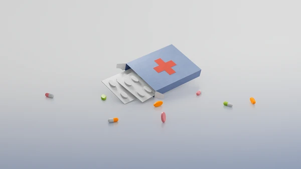 Eine geöffnete blaue Medikamentenpackung mit rotem Kreuz, aus der Blister mit runden Tabletten herausragen, umgeben von bunten Pillen und Kapseln.