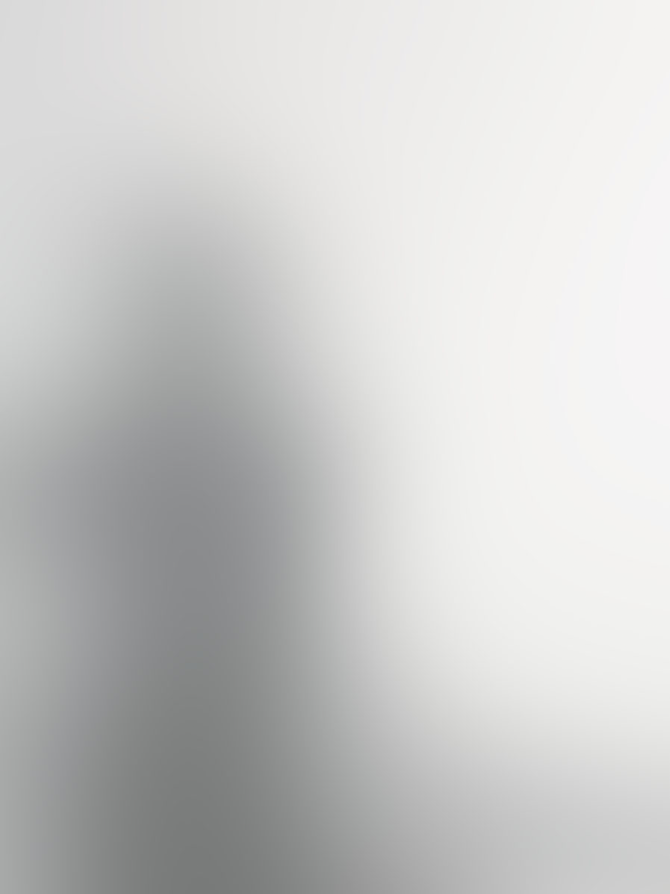 Das Bild zeigt eine unscharfe, minimalistische Darstellung, vermutlich einer Person oder eines Objekts in einer hellen, einfarbigen Umgebung.